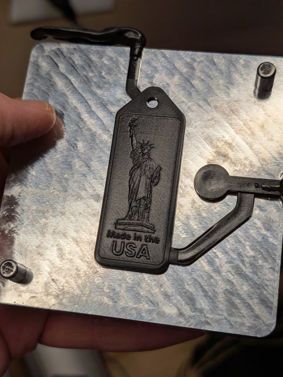 A freshly molded black keychain sitting in the open mold half